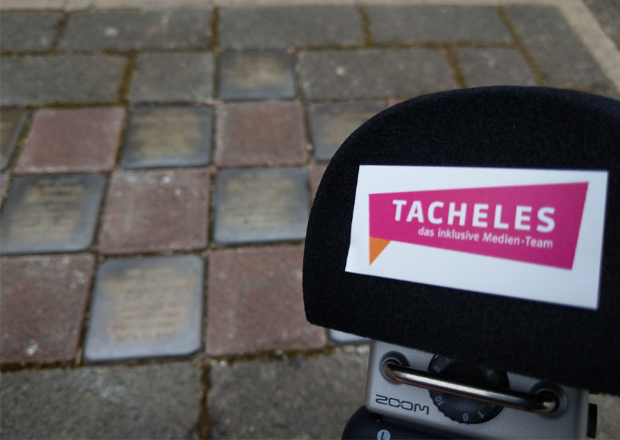 TACHELES-Logo auf dem Plopp-Schutz eines Audio -Aufnahme-Geräts, im Hintergrund einige Stolpersteine im Boden