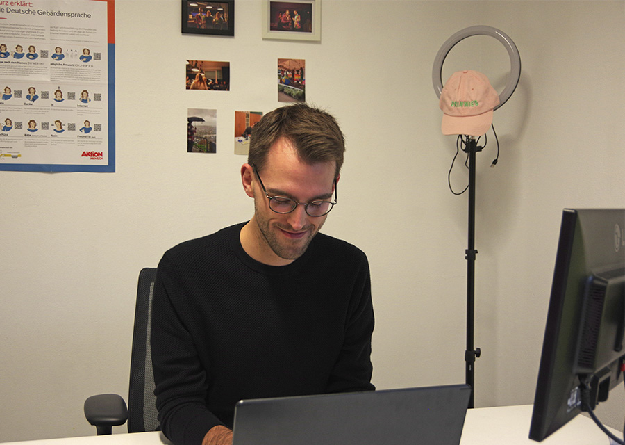 Adrian Schneider an seinem Arbeitsplatz vor einer Wand, schreibt am Laptop