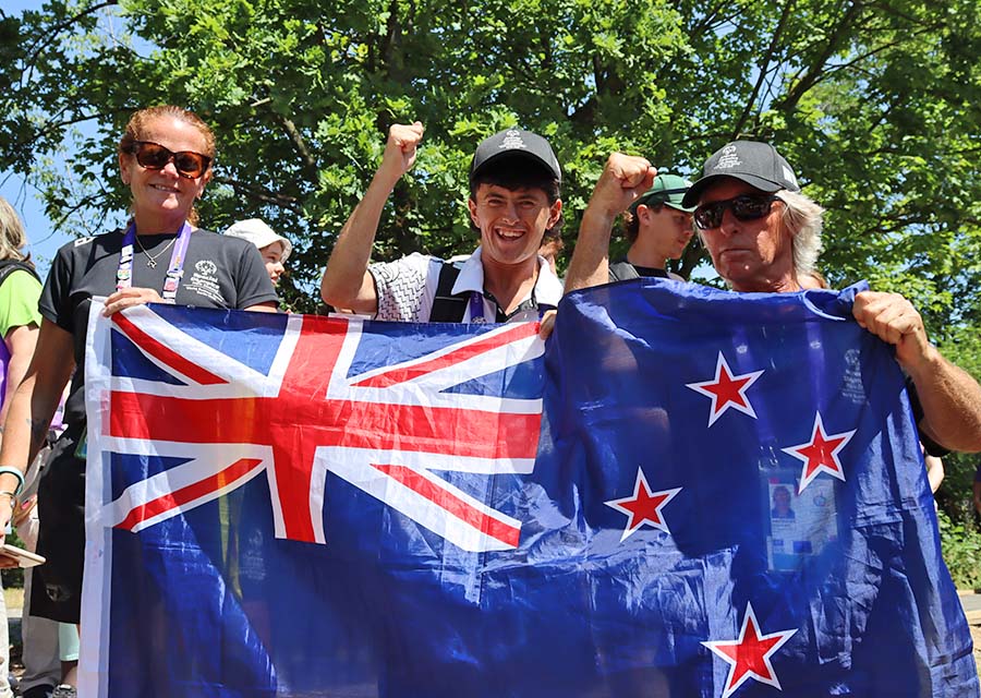 Drei Leute jubeln mit einer Neuseeland-Flagge
