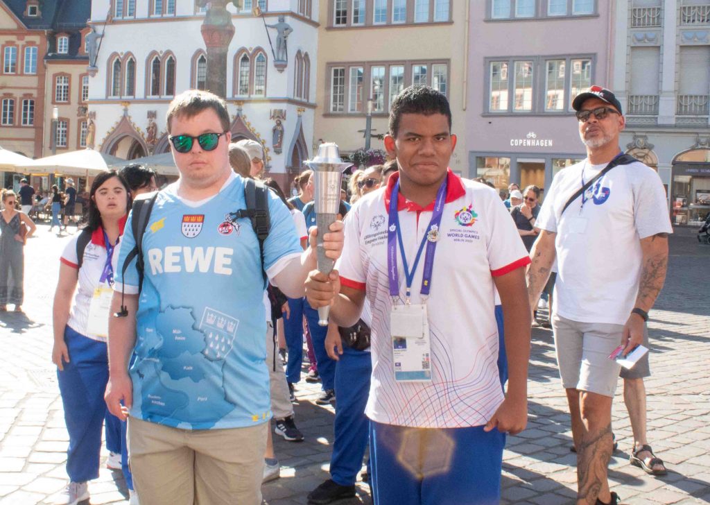 Ein panamischer und ein deutscher Athlet halten gemeinsam die Fackel