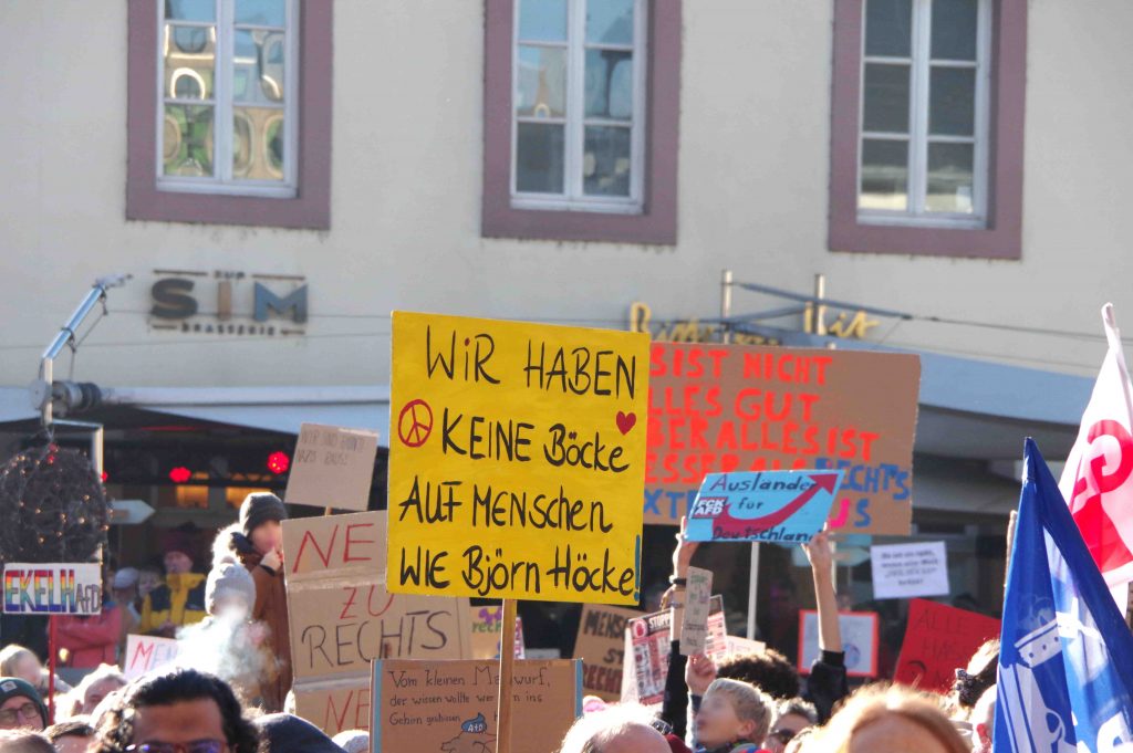 Protest-Schilder gegen die AfD über den Köpfen der Menschen