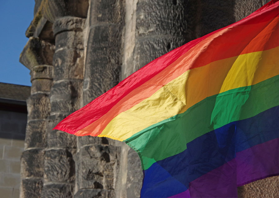 Eine Regenbogen-Flagge vor der Porta Nigra