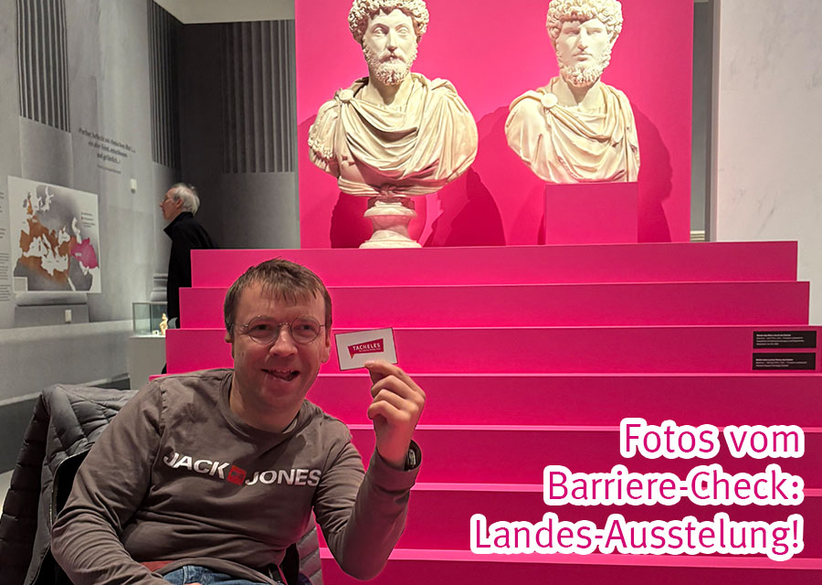 Patrick steht vor einer TACHELES-farbenen Treppe in Magenta und hält eine TACHELES-Karte in die Kamera