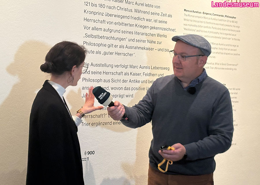 Marc vom SWR interviewt eine schicke Frau vom Landesmuseum