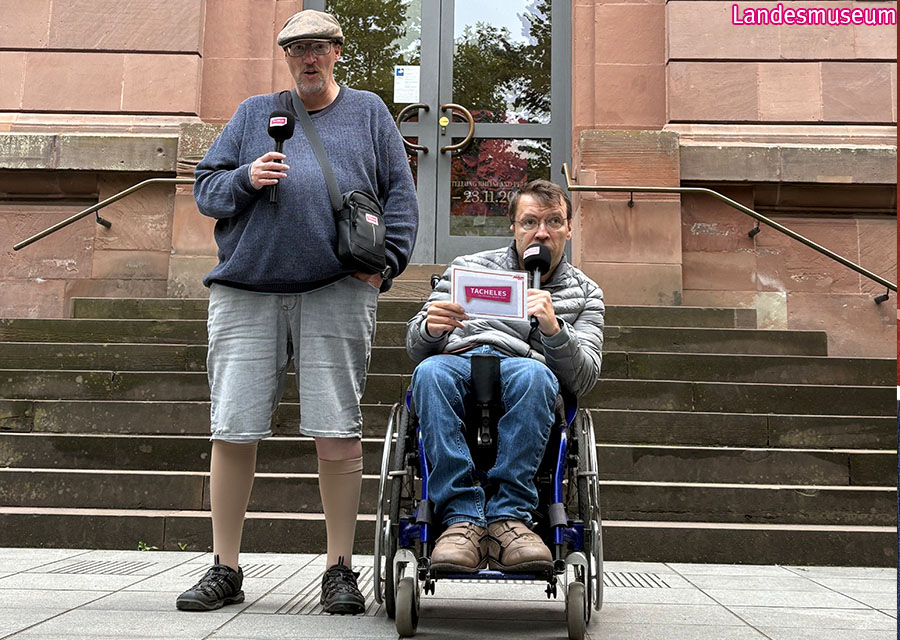 Heinrich und Patrick moderieren mit Mikrofon vor dem Eingang zum Landesmuseum