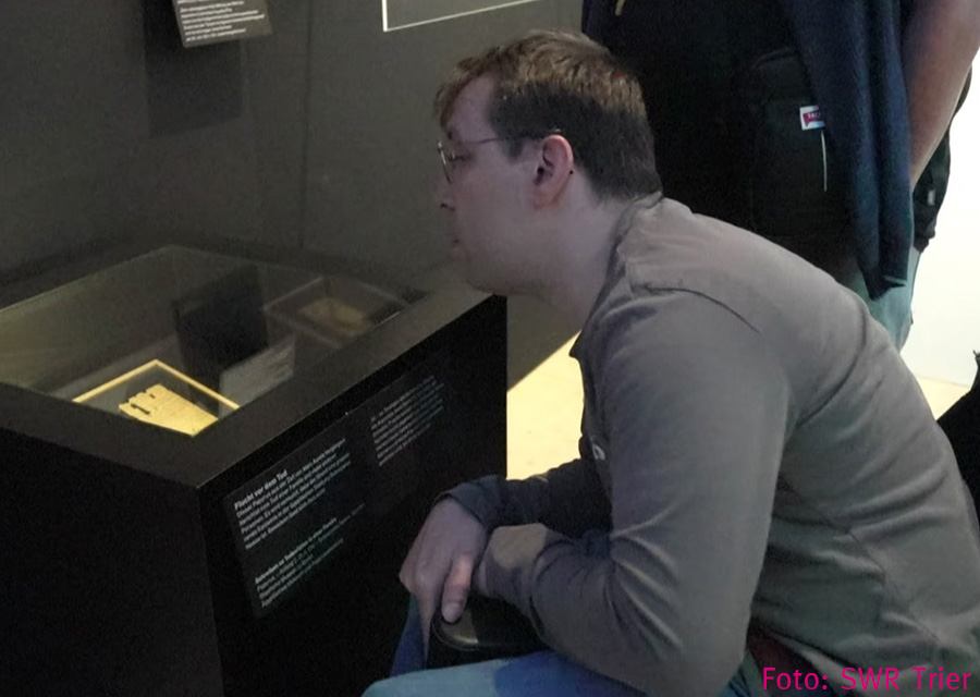Patrick reckt sich weit, um von oben in eine Vitrine schauen zu können