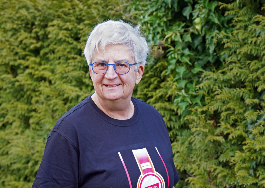 Redakteurin Gaby im TACHELES-TShirt vor grüner Hecke