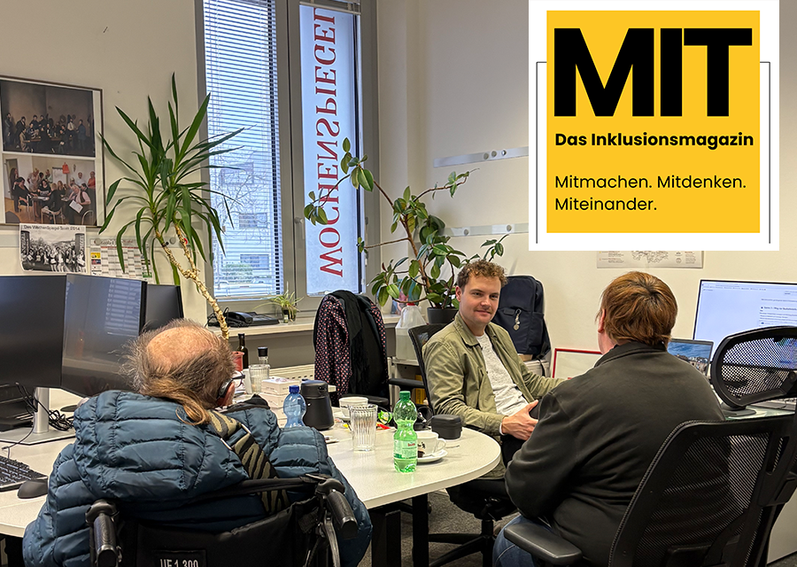 Über die Schultern von TACHELES-Reporter Wolfgang (links) und Heike (rechts) sieht man in ein Büro mit einem Tisch, hinten ein Fenster und kleine Palmen, dazwischen ein Wochenspiegel-Redakteur