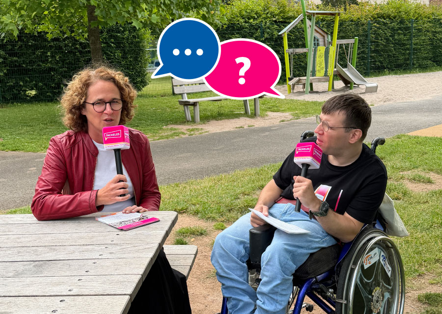 Eine Frau und Patrick von TACHELES sitzen an einem Holztisch auf einem Spielplatz im Freien. Beide halten ein Mikrofon mit TACHELES Logo in der Hand. Patrick sitzt im Rollstuhl. Zwischen den beiden sind zwei Sprechblasen in blau und pink mit Punkten und Fragezeichen. Im Hintergrund sieht man Wiese, grüne Hecken, eine Bank und Spielgeräte.